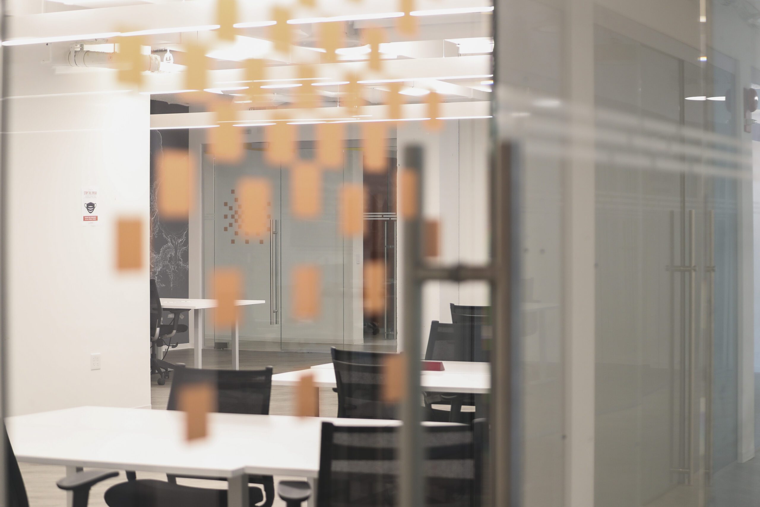 a view of a launch workplaces coworking location looking through a glass door into the open floor plan area with dedicated desks and coworking desks