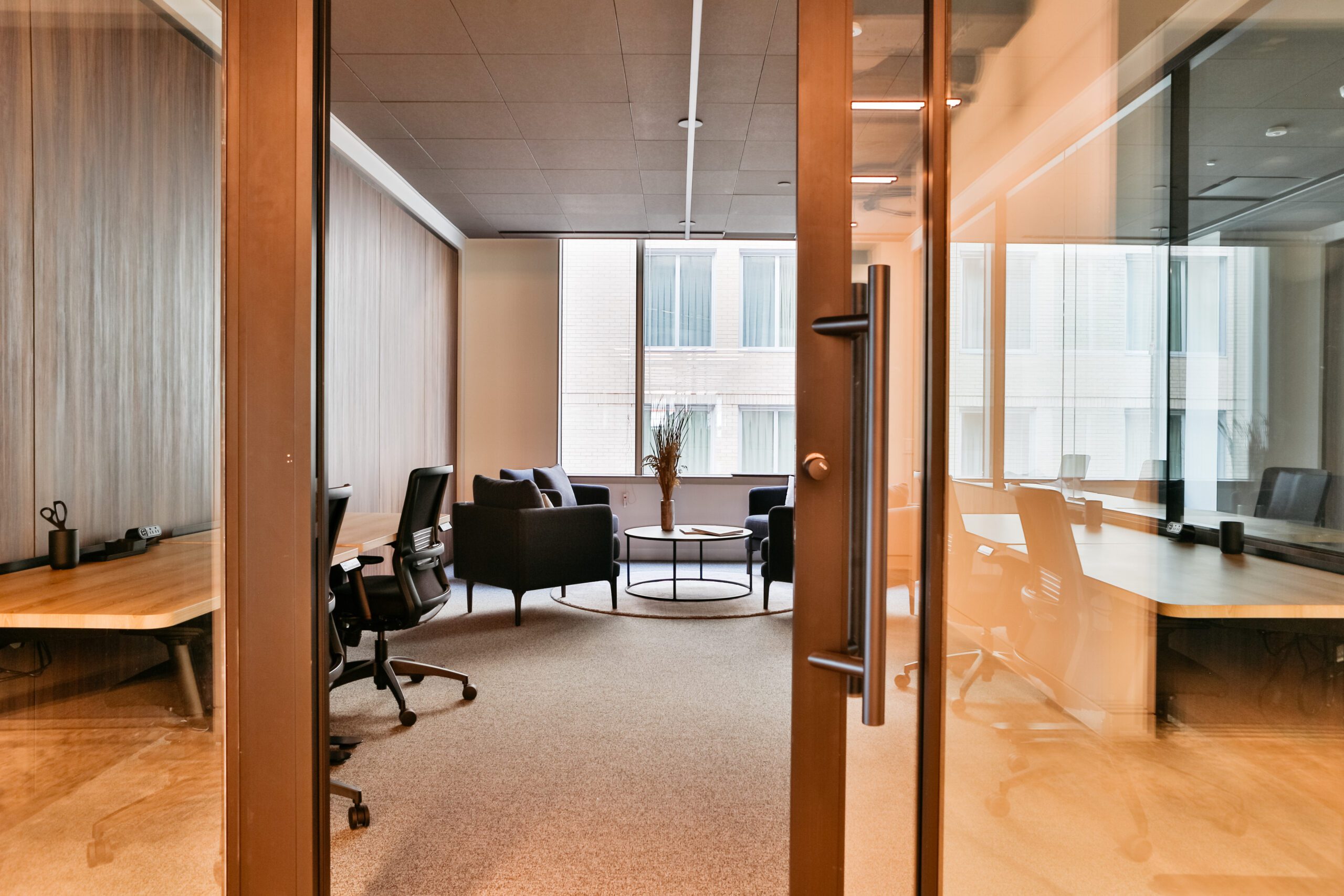 a well appointed workspace space in a coworking space for office leasing with multiple seating areas and beautiful warm wood walls and glass doors